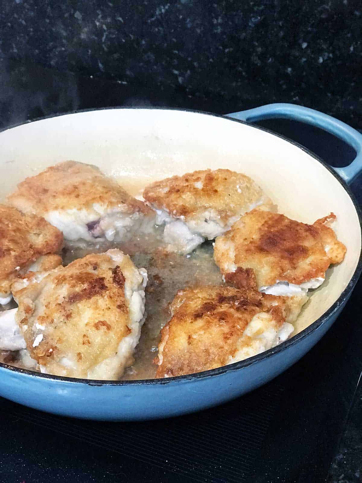 Browned in-bone chicken thighs in the pan.