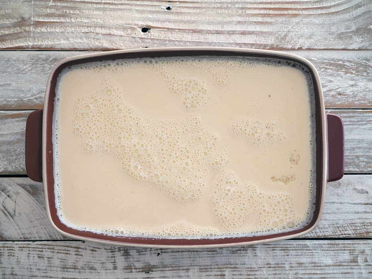 Milk mixture added to the baking dish with rice.