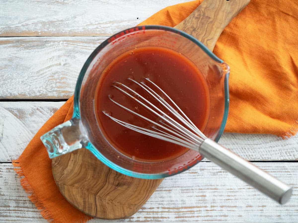 Mixing the stock cube with water and tomato paste in a jug with a whisk.