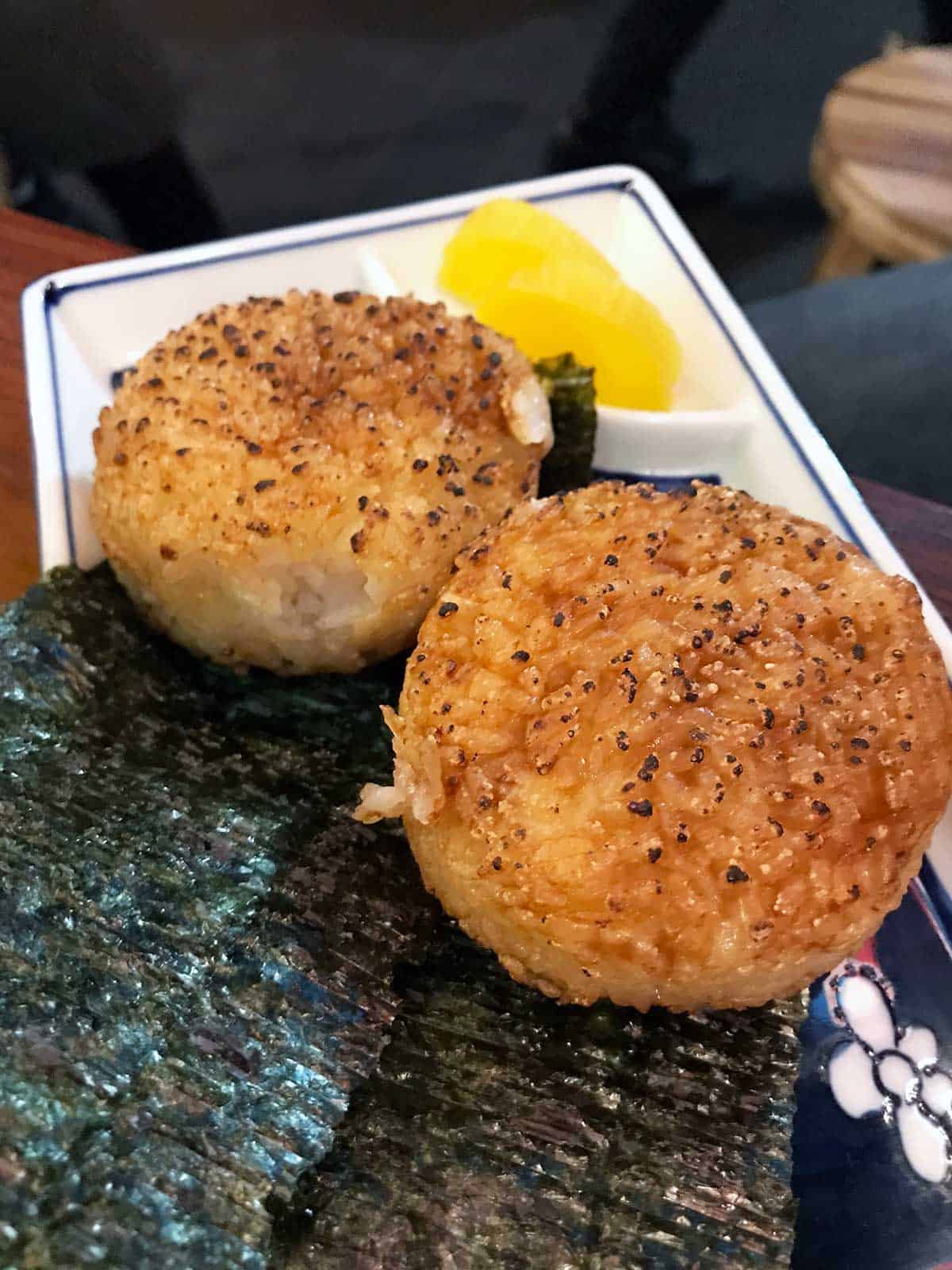 Two onigiri and pickles on a plate.