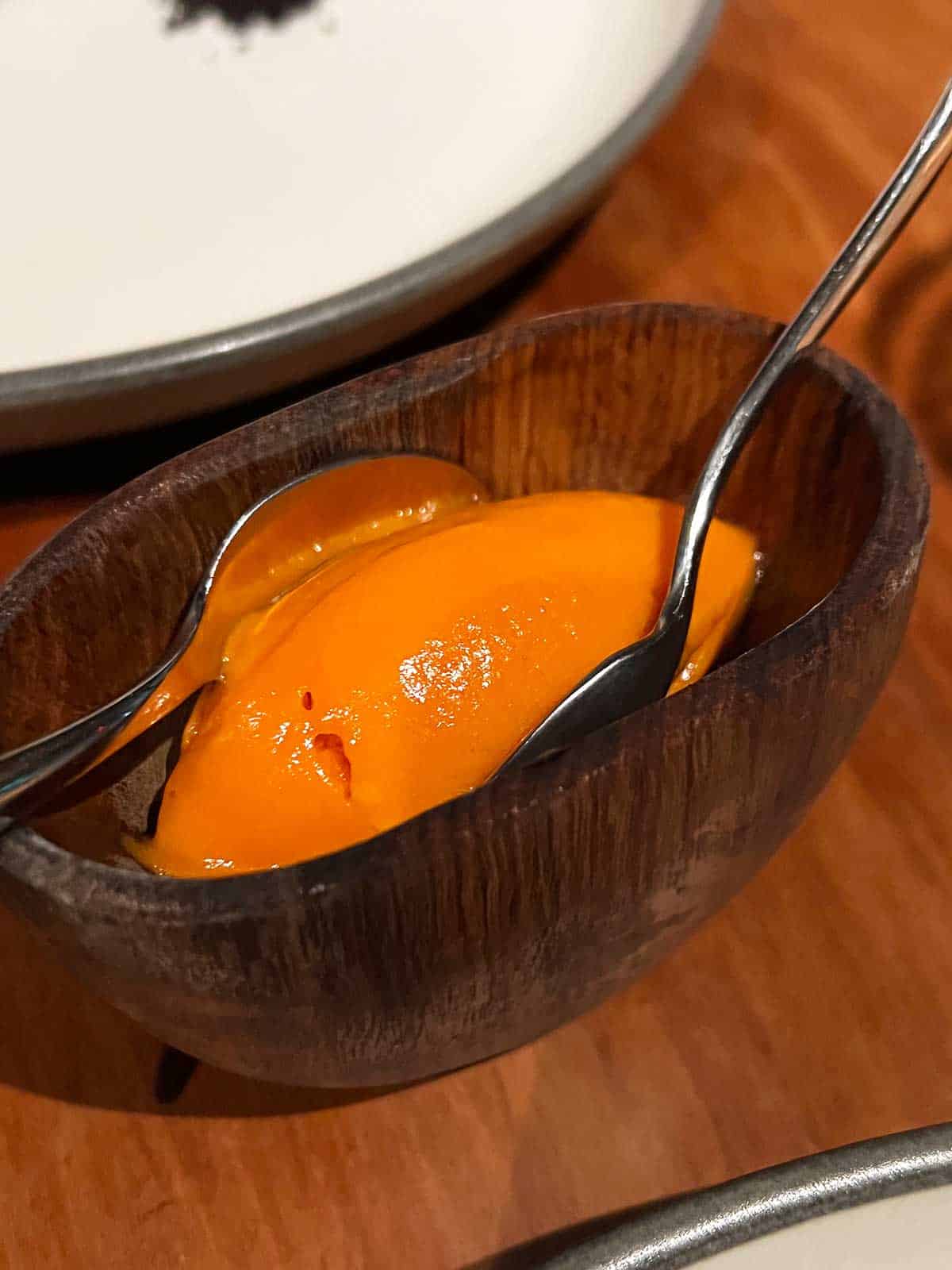 Carrot sorbet in a small bowl with a spoon.