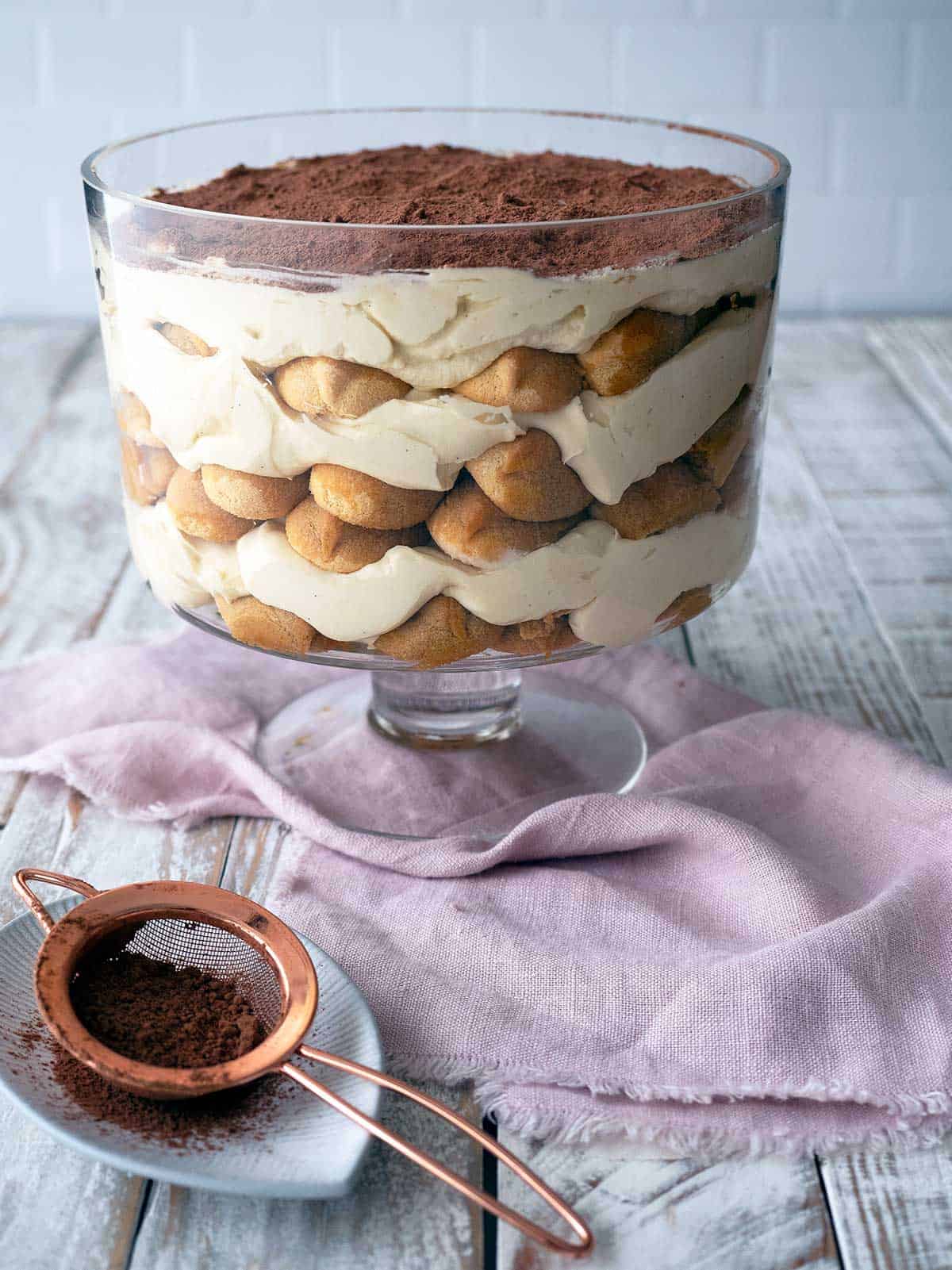 Eggless tiramisu ready to be served in a glass bowl.