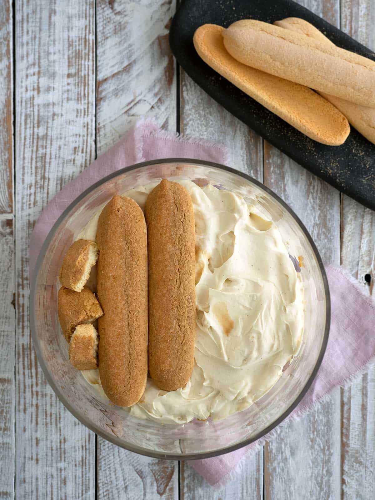 Layering the savoiardi biscuits with the cream mixture.