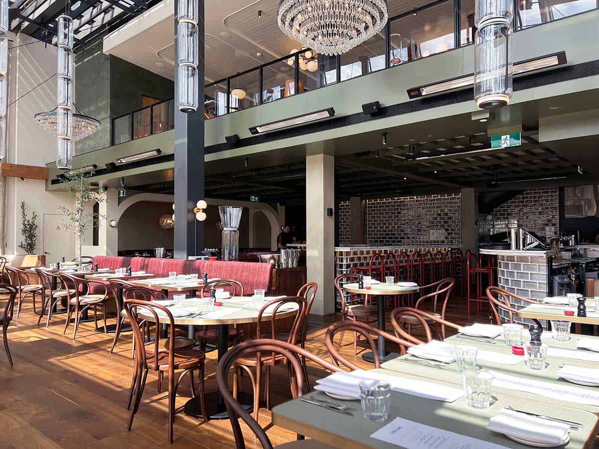 Dining tables at Origine French restaurant in Auckland with high ceilings and full length glass windows.