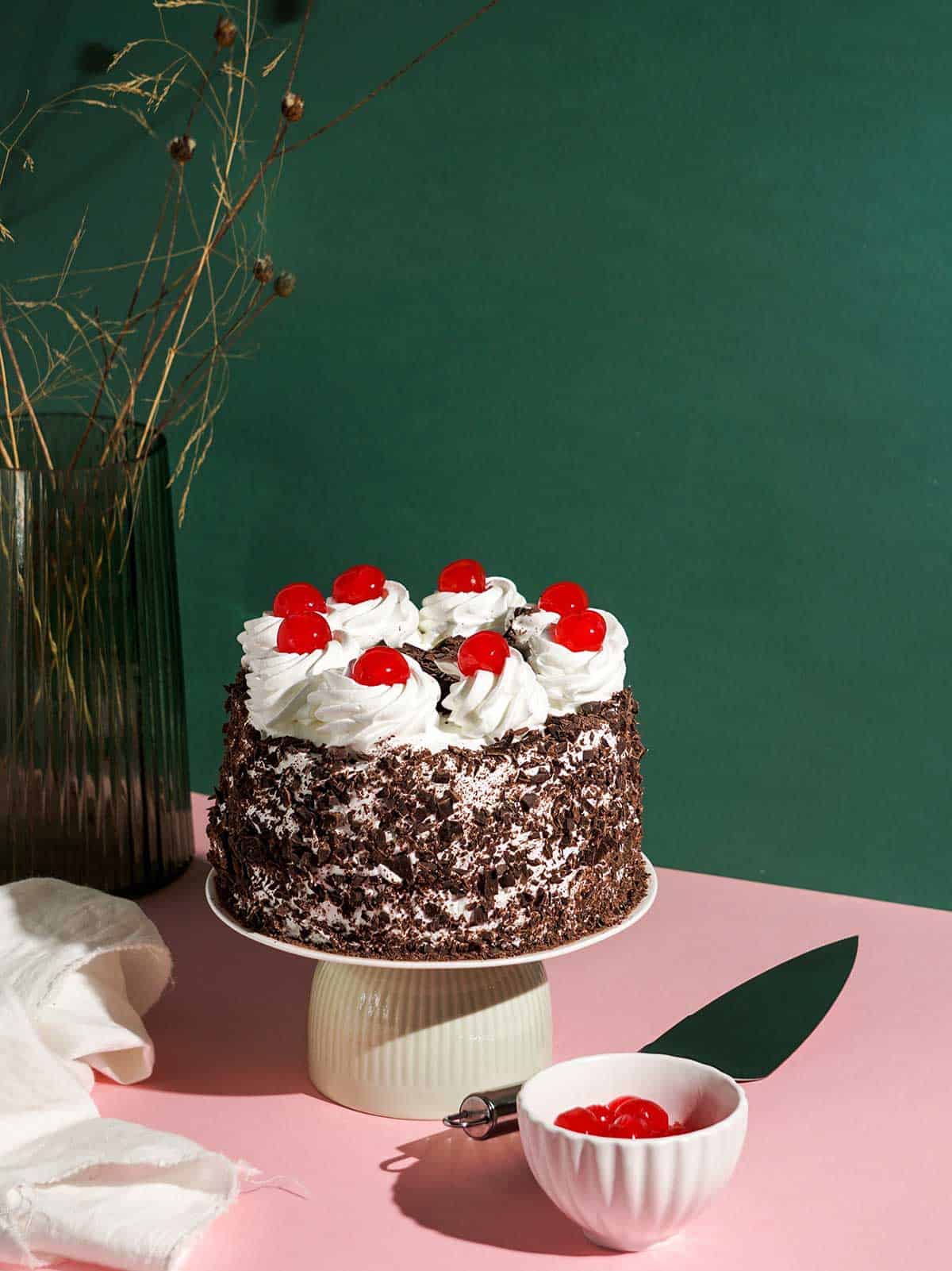 Cherry cake on cake stand with green background.