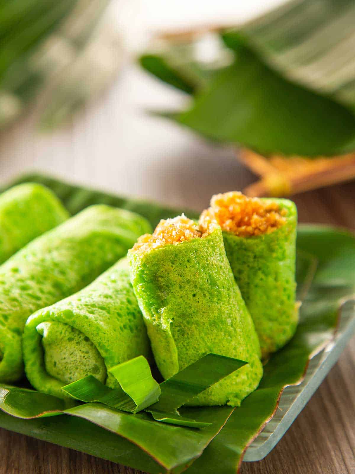 Dadar gulung sitting on a plate with banana leaves.