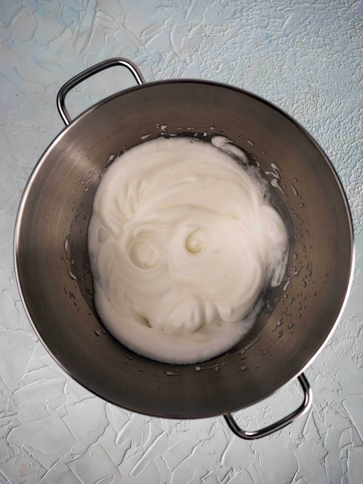 Whipped egg whites in a metal bowl.