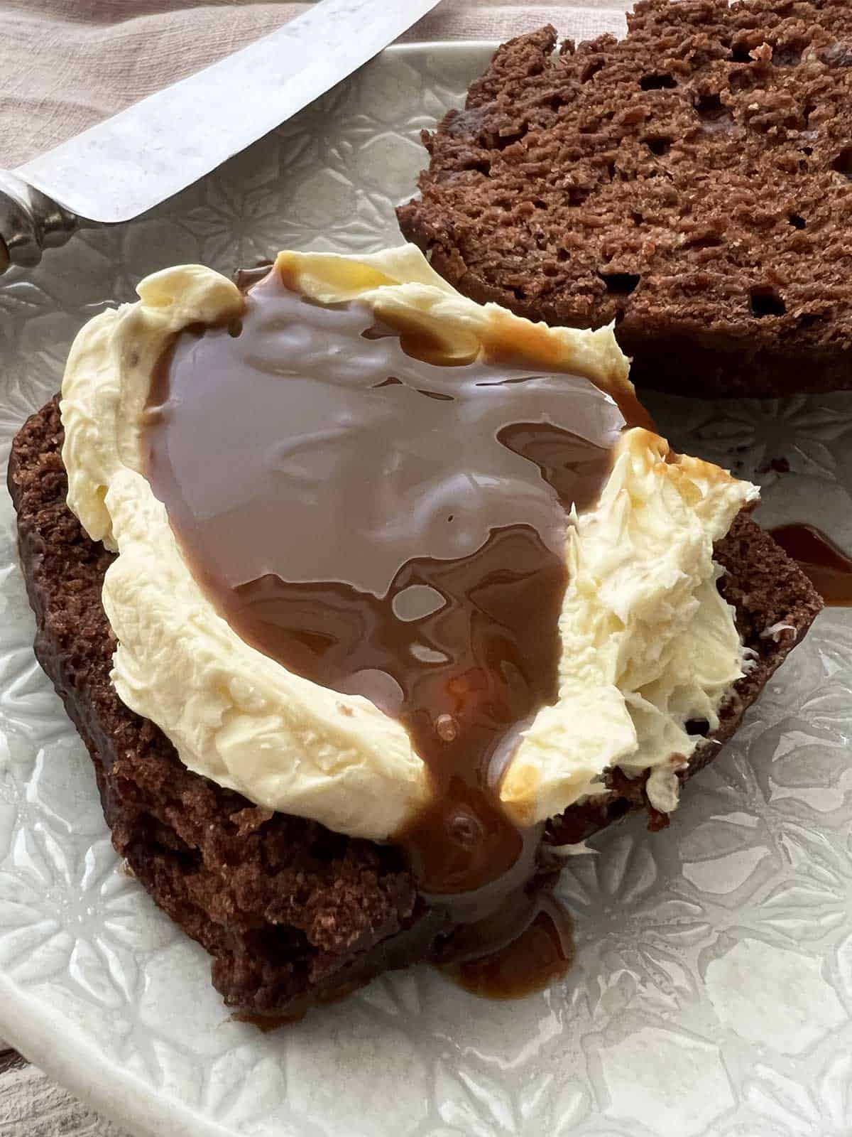 Chocolate scone split in half topped with whipped cream and caramel sauce.