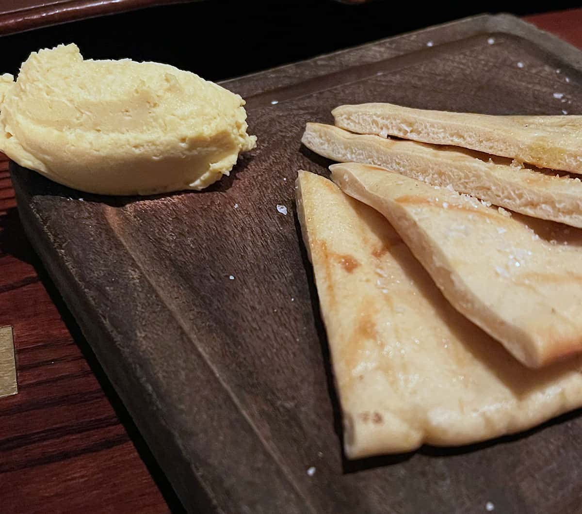 Flatbread with whipped hummus on a wooden board.
