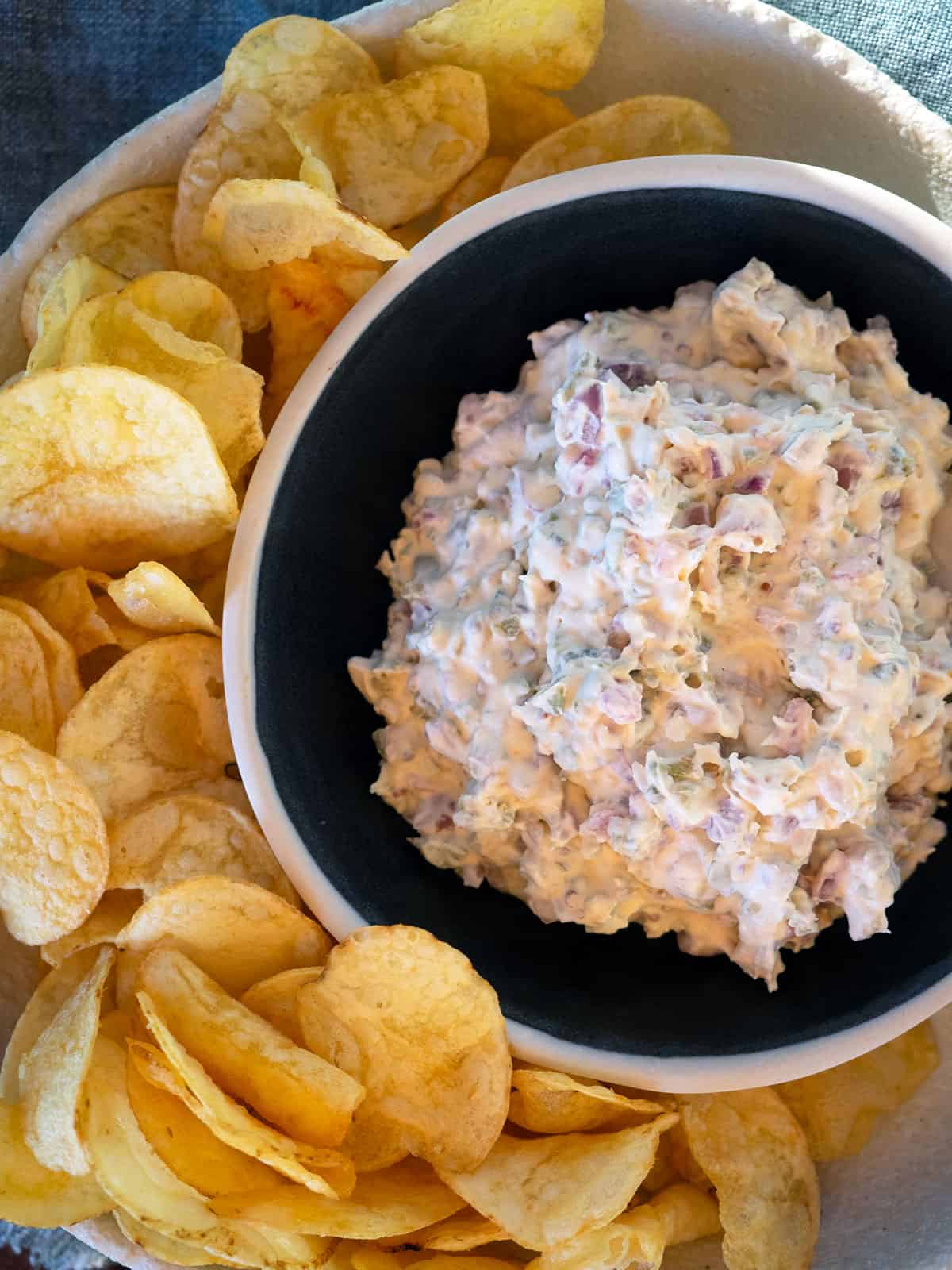 Black bowl with dip surrounded by thick cut chips.