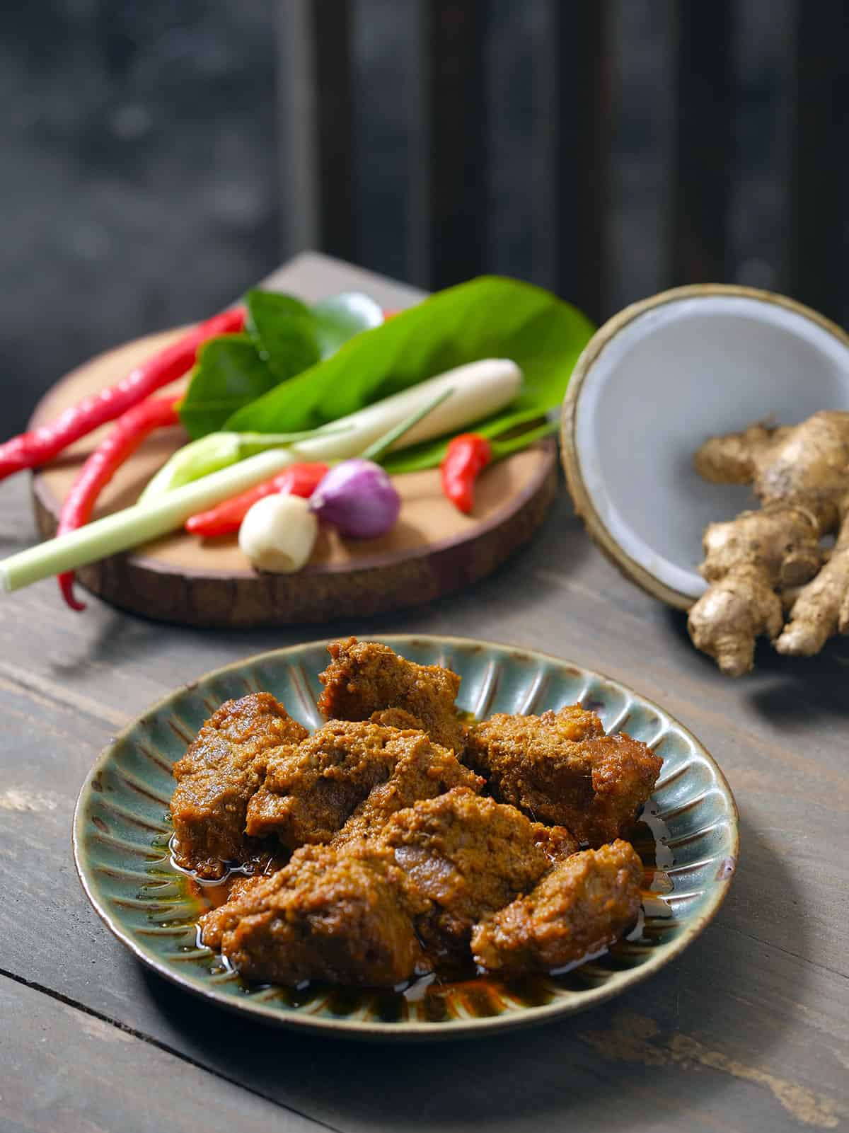 Beef rendang n a wooden board with ingredients.