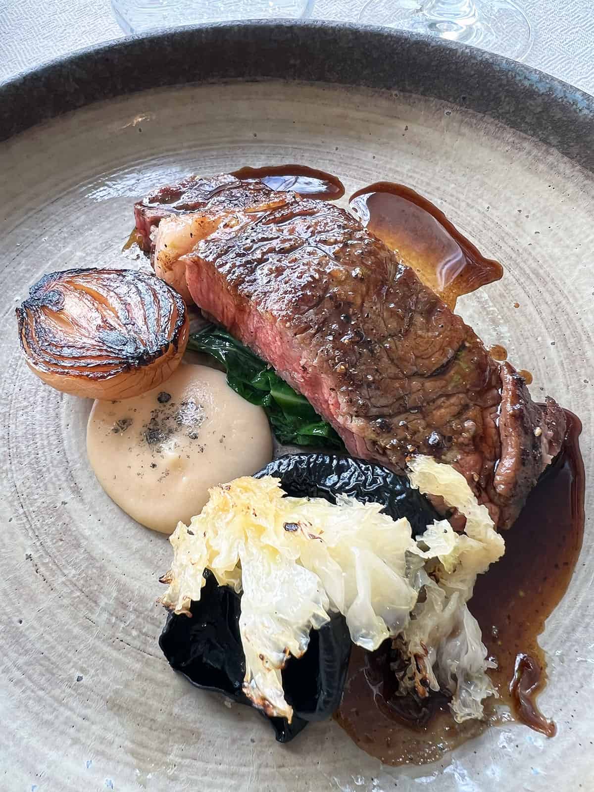 Scotch fillet with fungus, onion and puree on a plate.