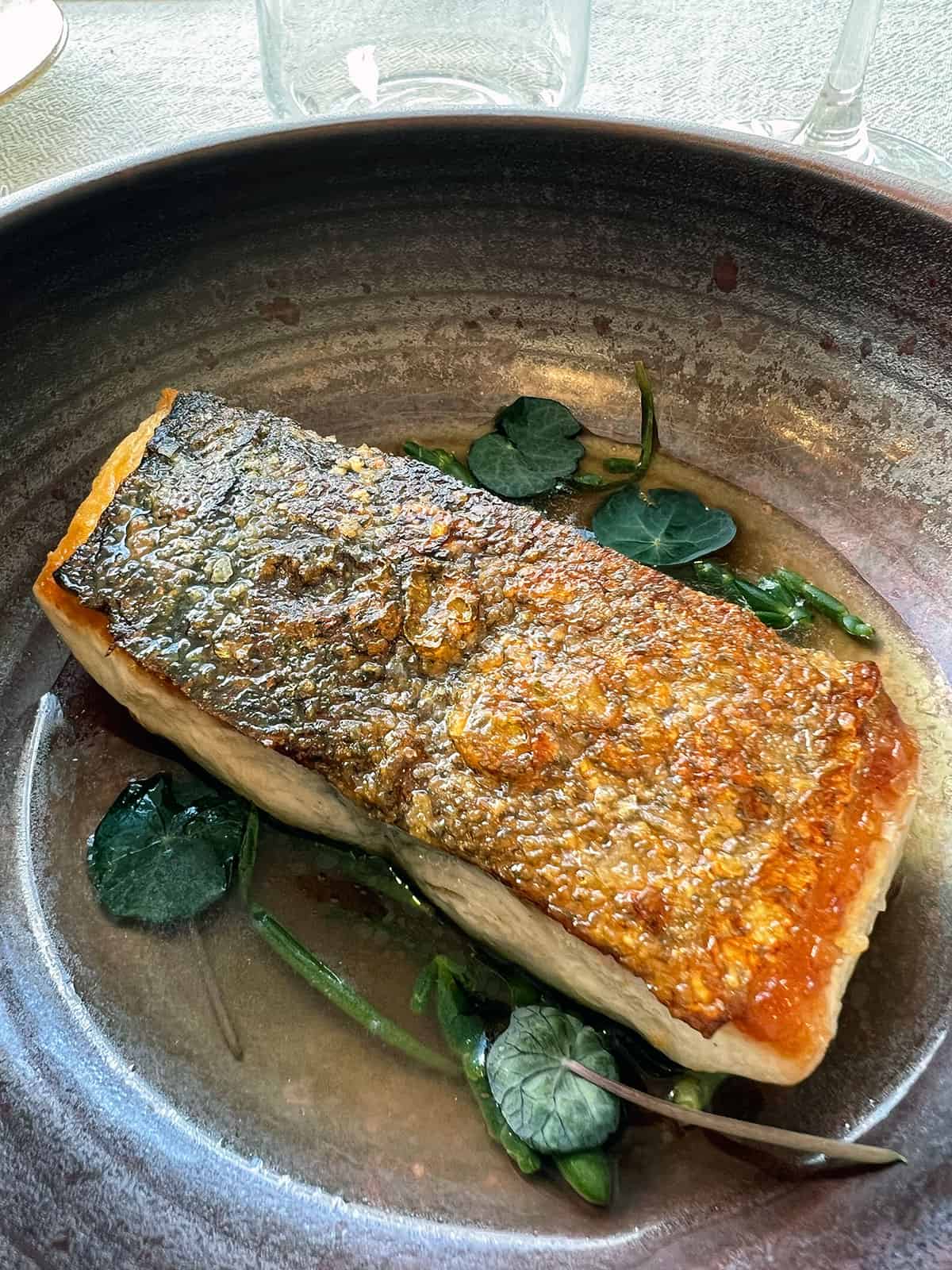 Hiramasa kingfish with crispy skin in a bowl with dashi and coastal herbs.